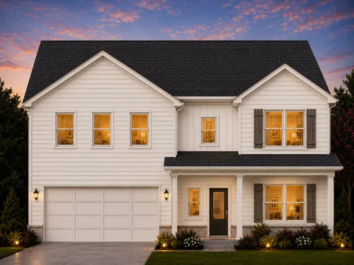 Two-story white house with black roof at sunset, warm interior lighting, front porch, and landscaped yard with flowers.